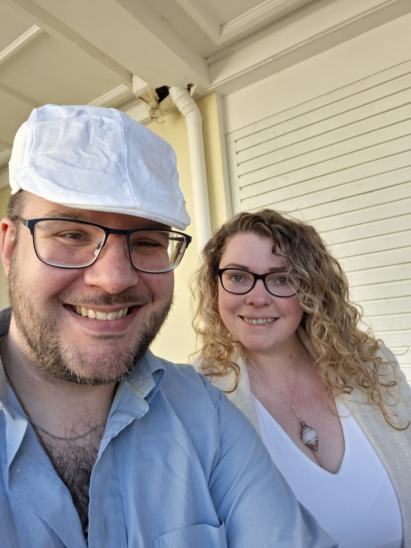 Adrian wearing glasses, blue shirt and white cap with his wife Louise with glasses, long curly brown hair and white top