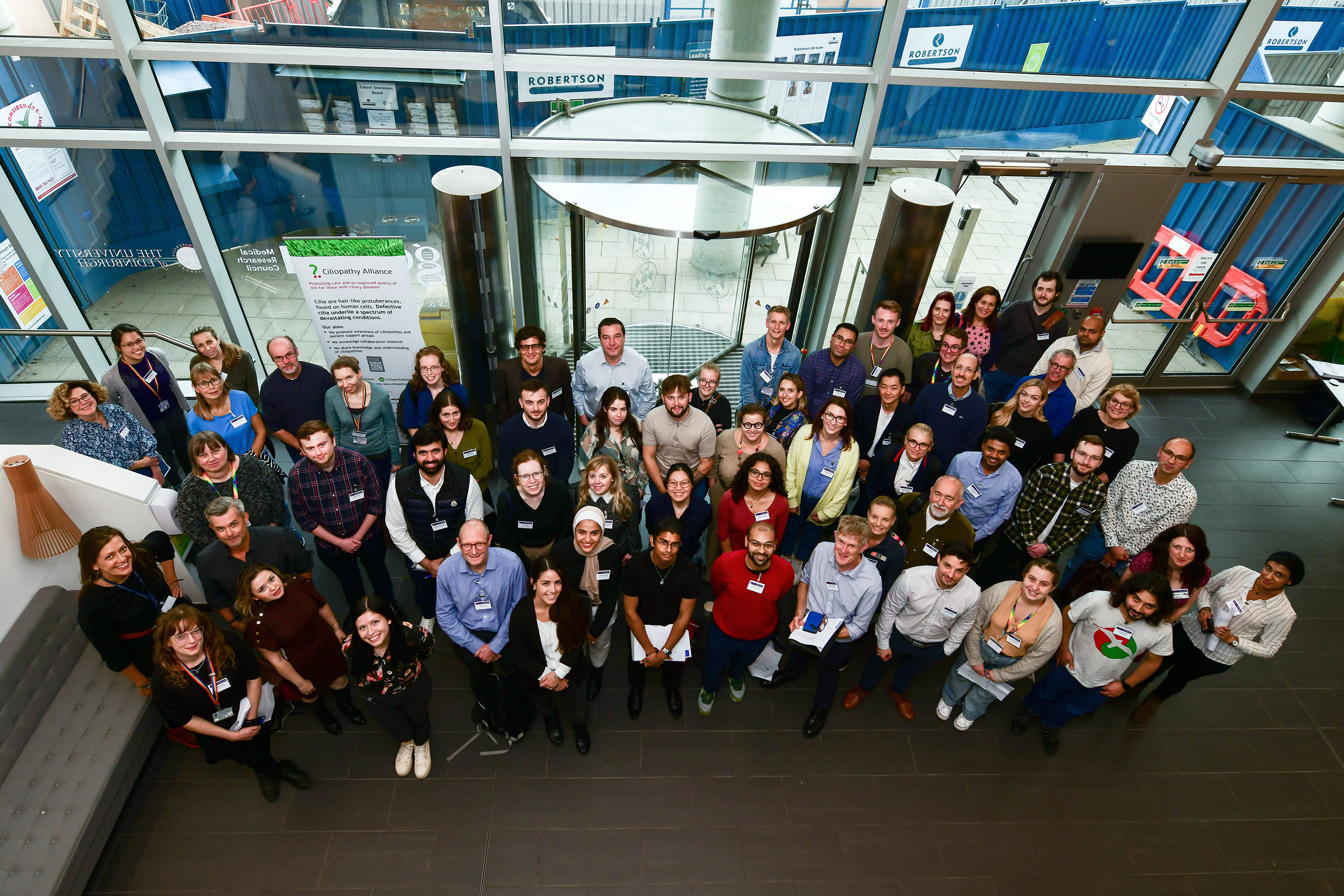75 attendees standing together looking up towards camera